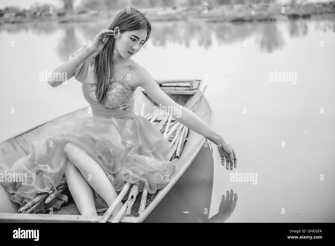 Porträt von Asien schöne Frau im gelben Kleid sitzt auf Boot, schwarz / weiß Bild Stockfoto