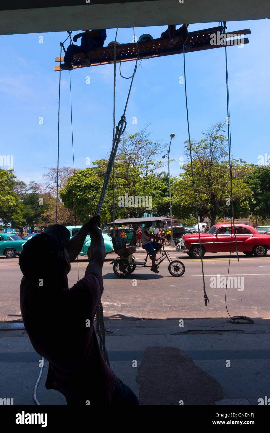 Ein Mann hält eine Leiste für Bauarbeiter, die Wartungsarbeiten an der Seite eines Gebäudes. Havanna, Kuba. Stockfoto