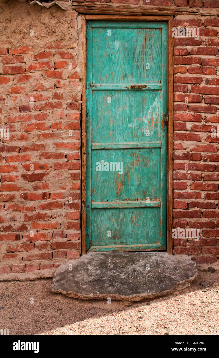 Alt, aber immer noch hell grüne Tür. Eingang zu einem Beduinen-Haus in einem Dorf in der Wüste in Ägypten. Haus aus Ziegeln. Stockfoto