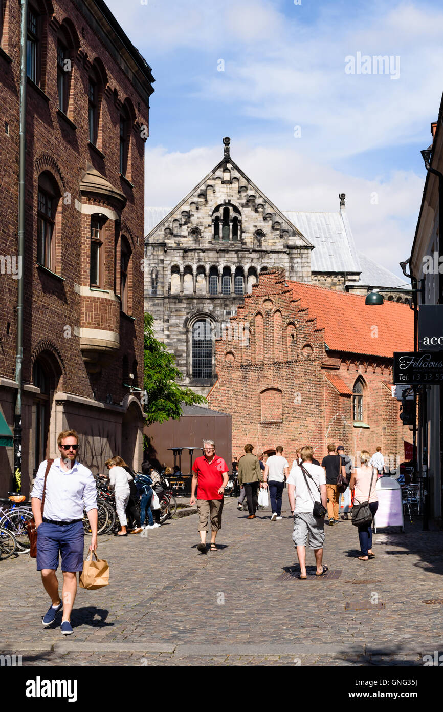 Lund, Schweden - 24. August 2016: Menschen zu Fuß entlang einer Straße in der Stadt mit einem Teil der Kathedrale im Hintergrund sichtbar. Stockfoto