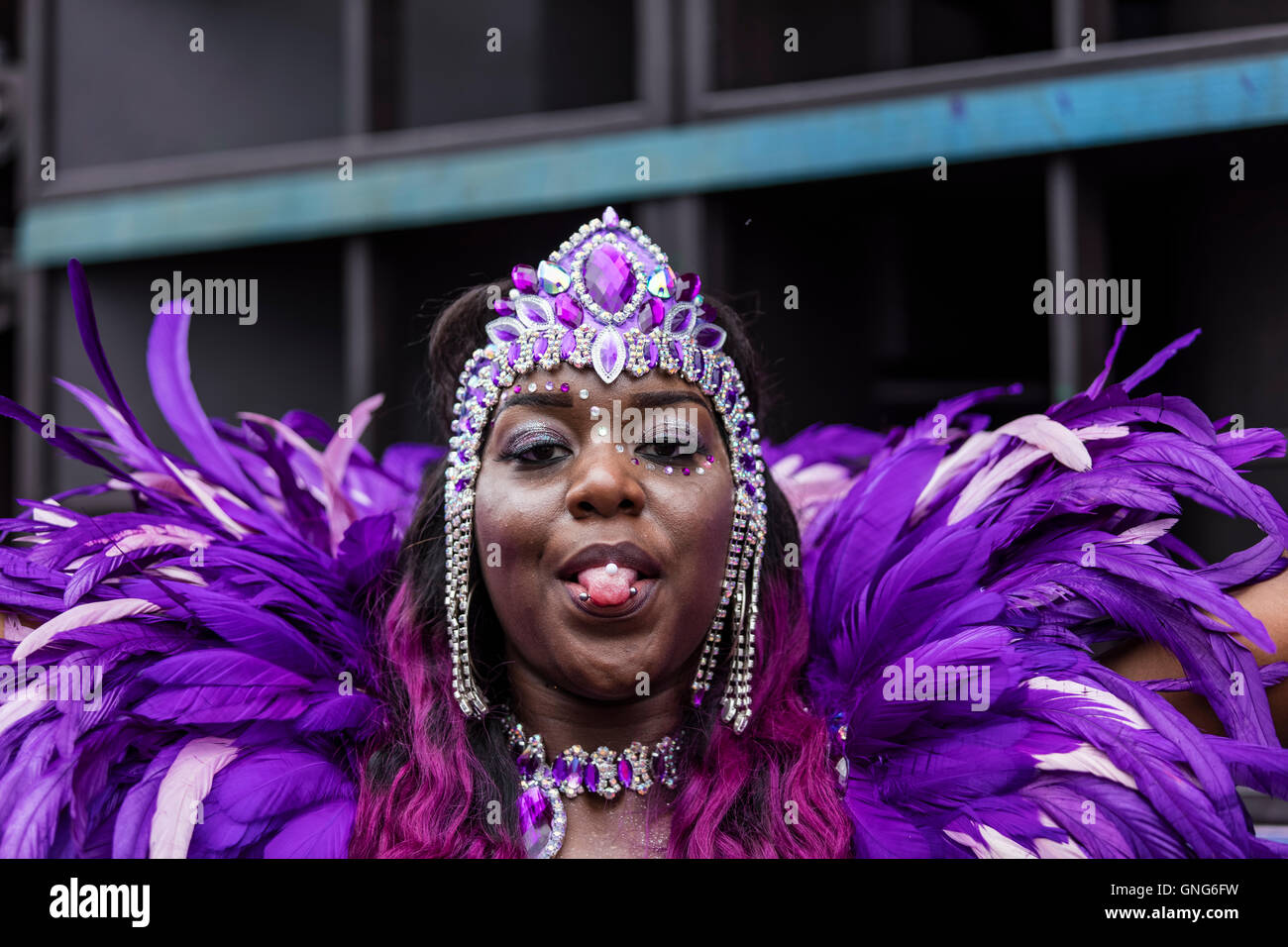 West Indies Karibik Dame in lila Feder Kostüm auf dem Notting Hill Carnival mit Nieten in ihrer Zunge Stockfoto