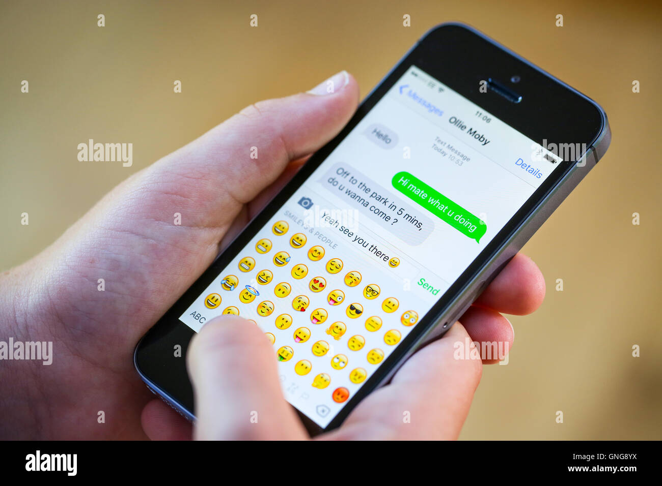 Ein Teenager mit einem Emoji während SMS auf seinem Iphone Stockfoto