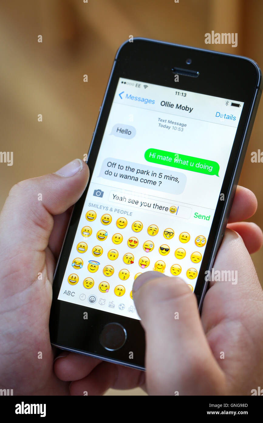 Ein Teenager mit einem Emoji während SMS auf seinem Iphone Stockfoto
