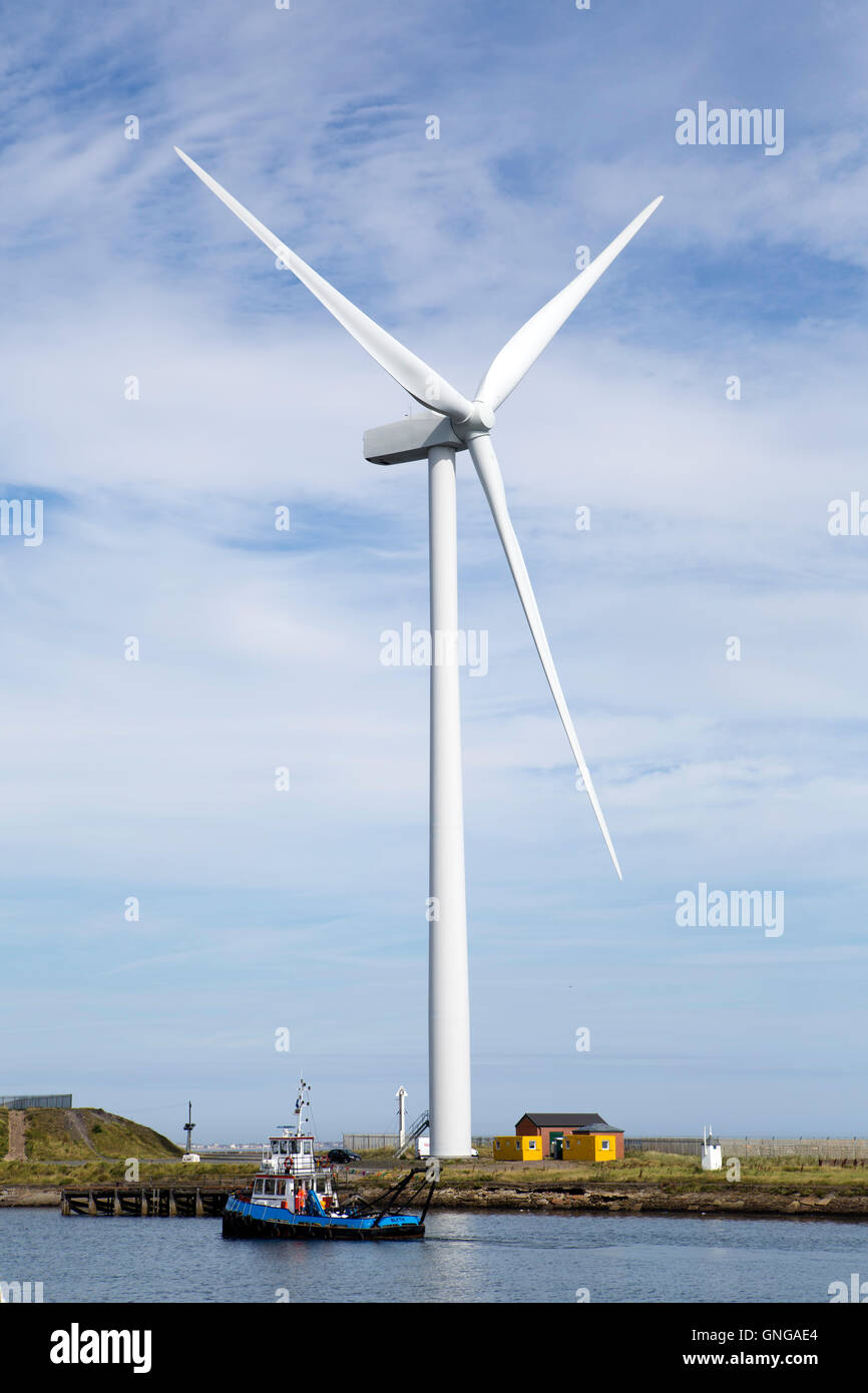 Ein Boot segelt unter einer Windkraftanlage in der Nordsee Tall Ships Regatta in Blyth in Northumberland, England. Stockfoto