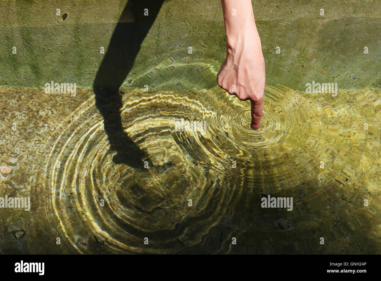 Person, die Finger machen Kreise in einem Wasserbrunnen Stockfoto