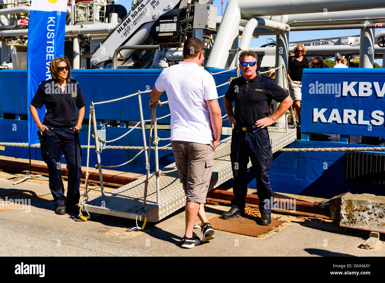 Karlskrona, Schweden - 27. August 2016: Küstenwache Personal begrüßen Besucher auf den öffentlichen offenen Schiff-Tag. Schiff im Hintergrund Stockfoto