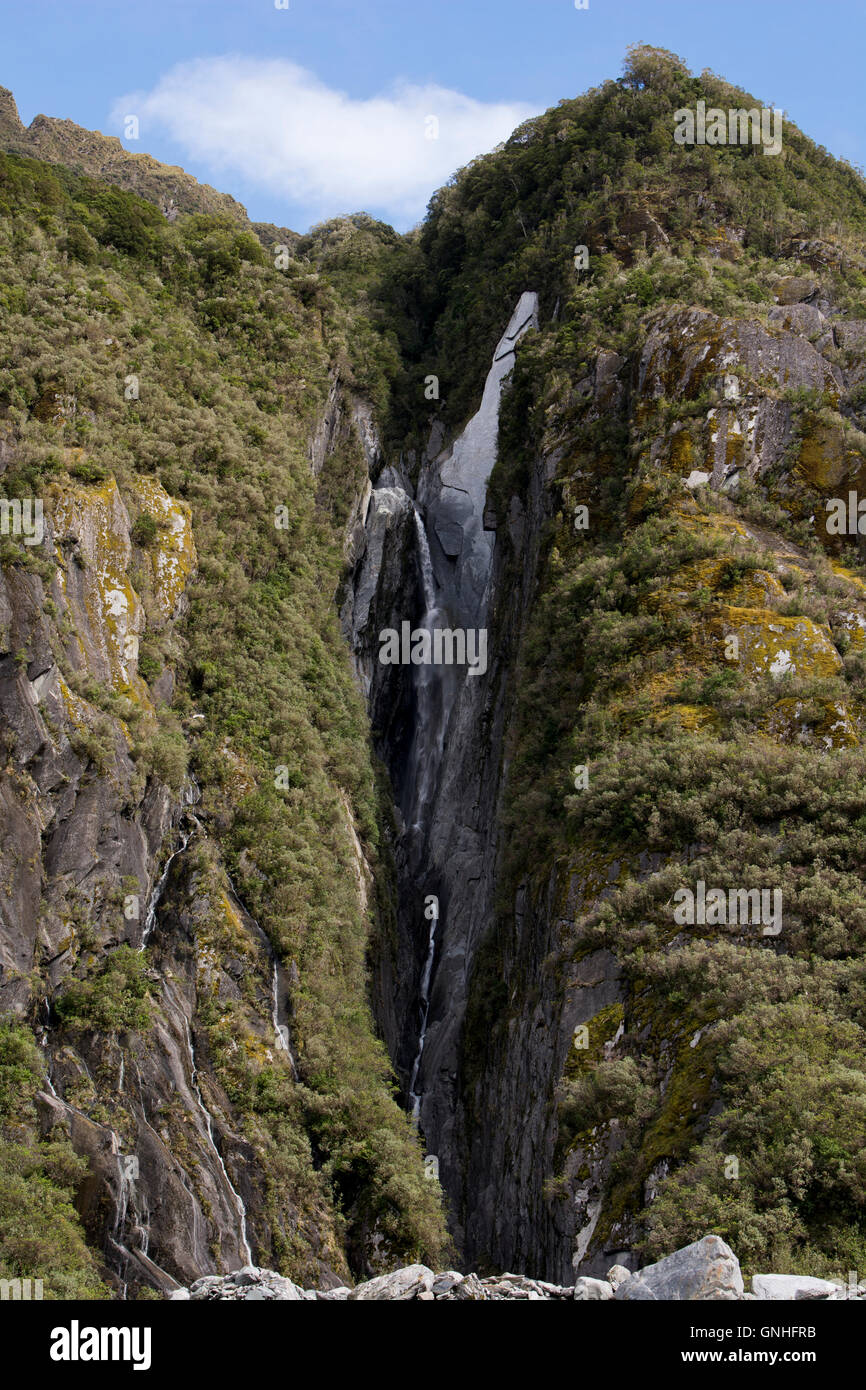 Gleich neben sind Franz Josef Glacier in den Südalpen Neuseelands Wasserfälle ins Tal donnern. Stockfoto