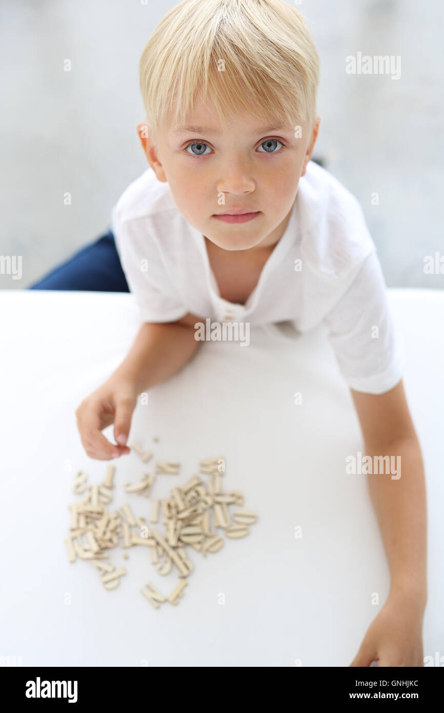 Glückliches Kind, spielerisch zu lernen. Vorschulkind Junge ordnet Puzzle. Stockfoto