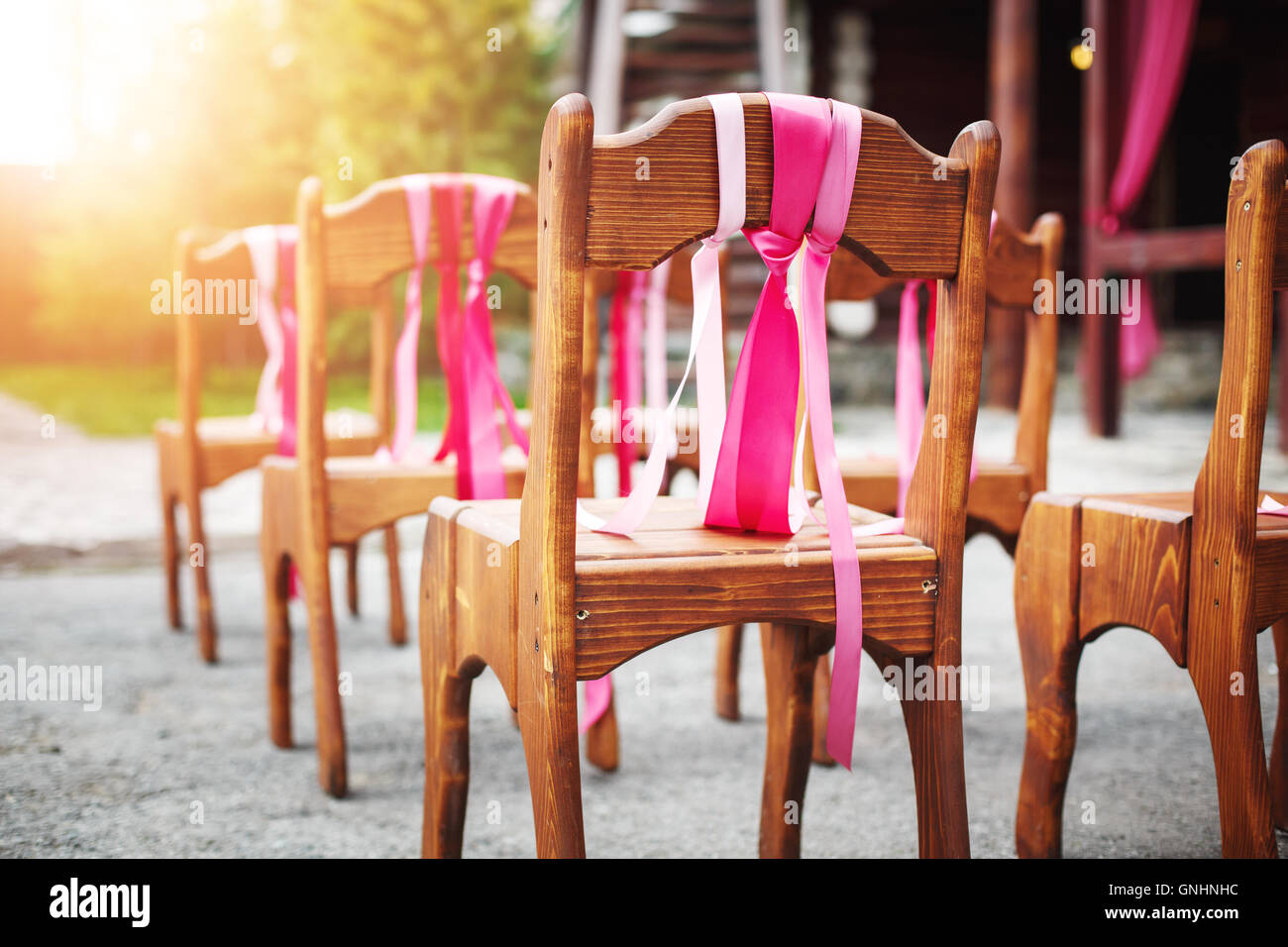 Schöne Holzstühle, geschmückt mit Bändern auf Hochzeitsfeier Stockfoto