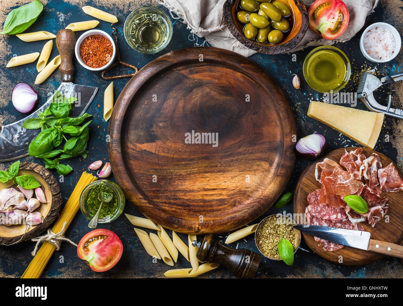 Italienische Küche kochen Zutaten auf dunklen Sperrholz Hintergrund mit runden Tablett aus Holz in der Mitte, Draufsicht, Textfreiraum, horizontale c Stockfoto