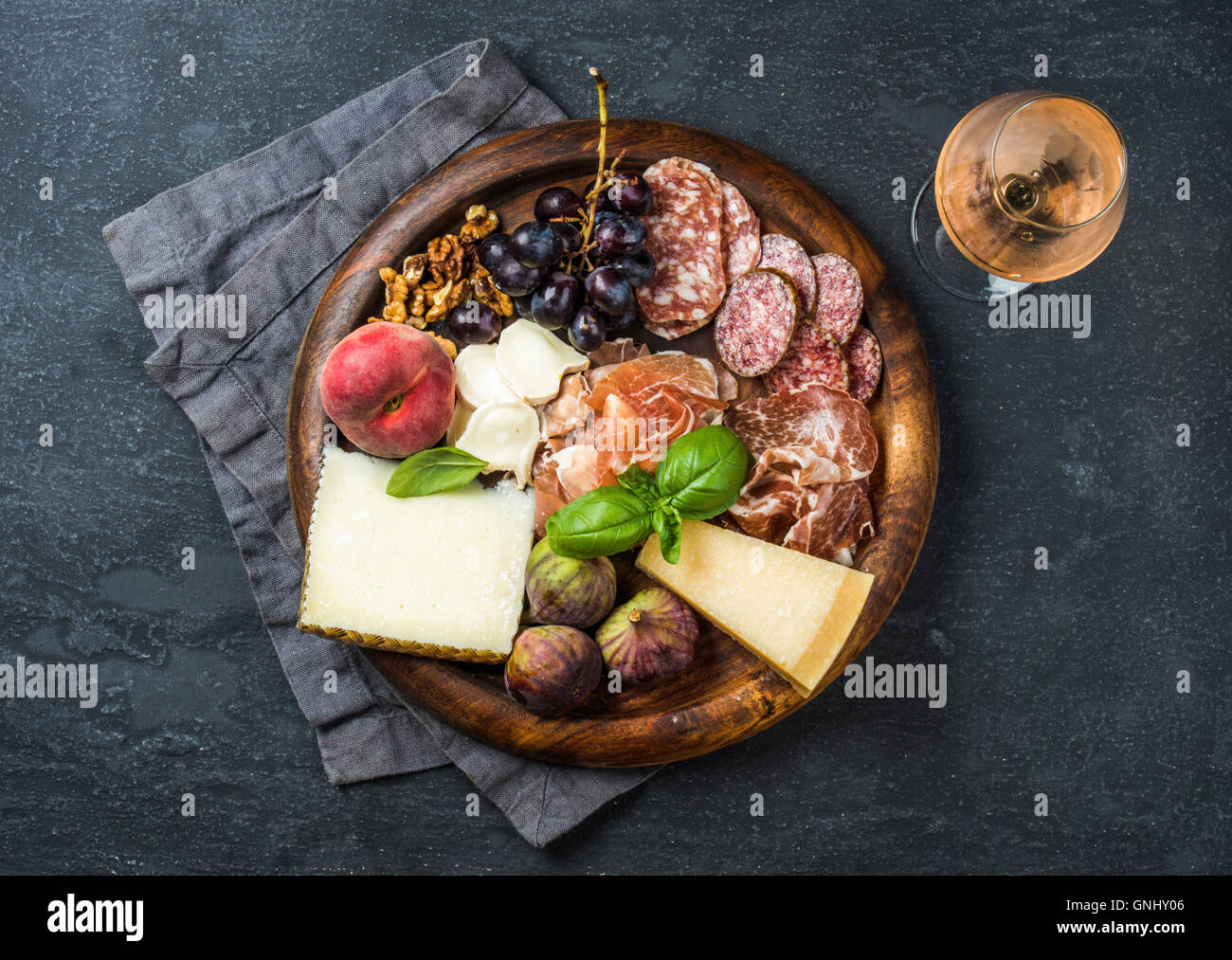 Italienische Antipasti snack für Wein. Parmaschinken, Salami, Käse-Vielfalt, Feigen, Trauben, Pfirsich, Walnüsse und frischem Basilikum auf w Stockfoto