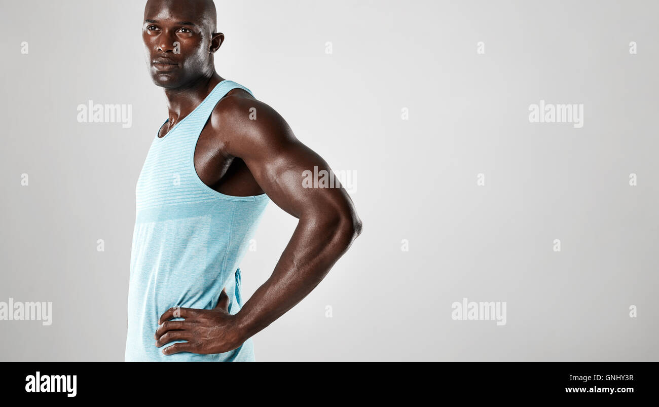 Porträt von Fit junger Mann muskulös steht vor grauem Hintergrund. Afro american Fitness-Modell mit Hände auf den Hüften ein Stockfoto