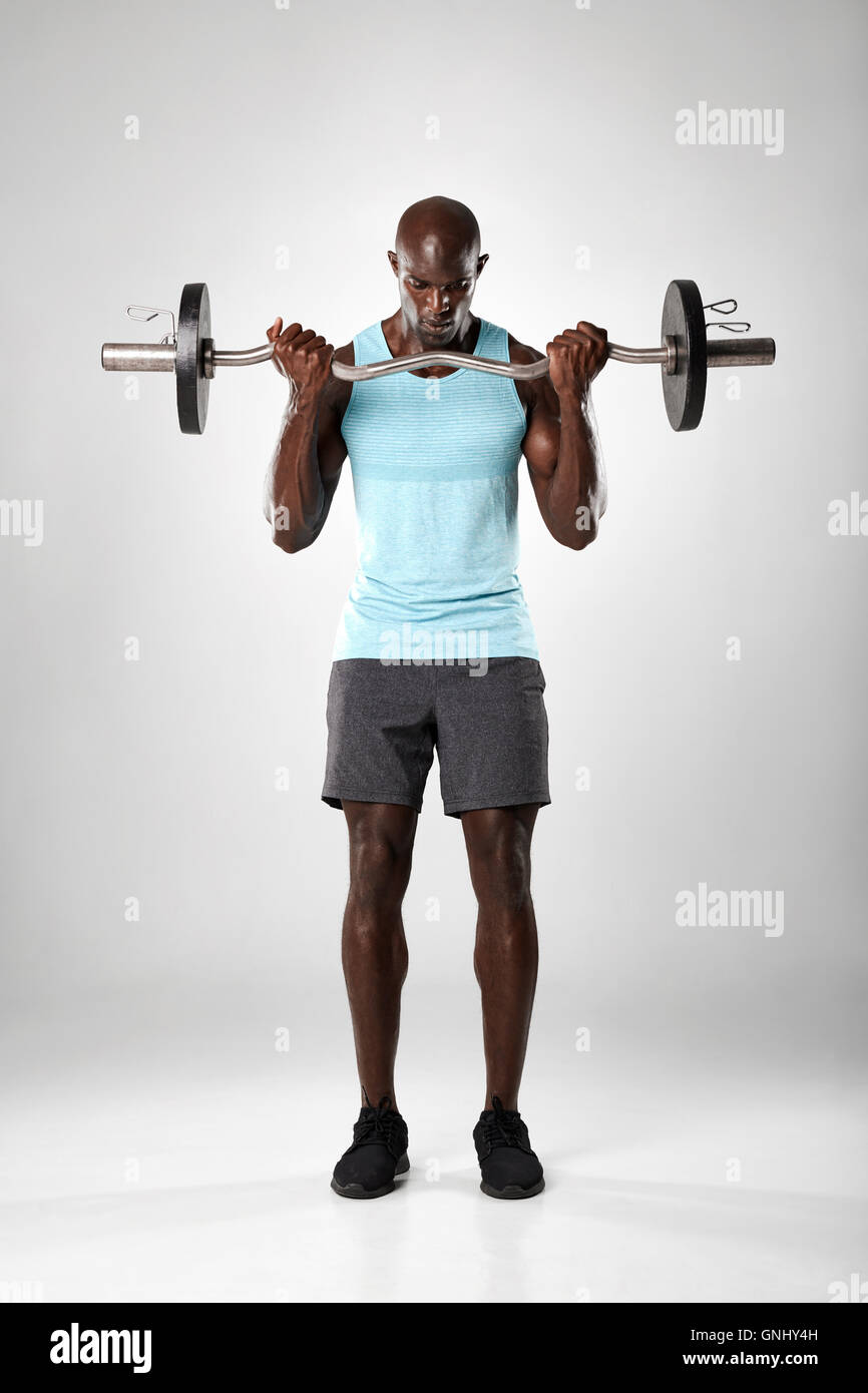 Gesamte Länge der jungen Afrikaner arbeiten mit Langhantel vor grauem Hintergrund. Muskulöser Mann Training mit Gewichten. Stockfoto