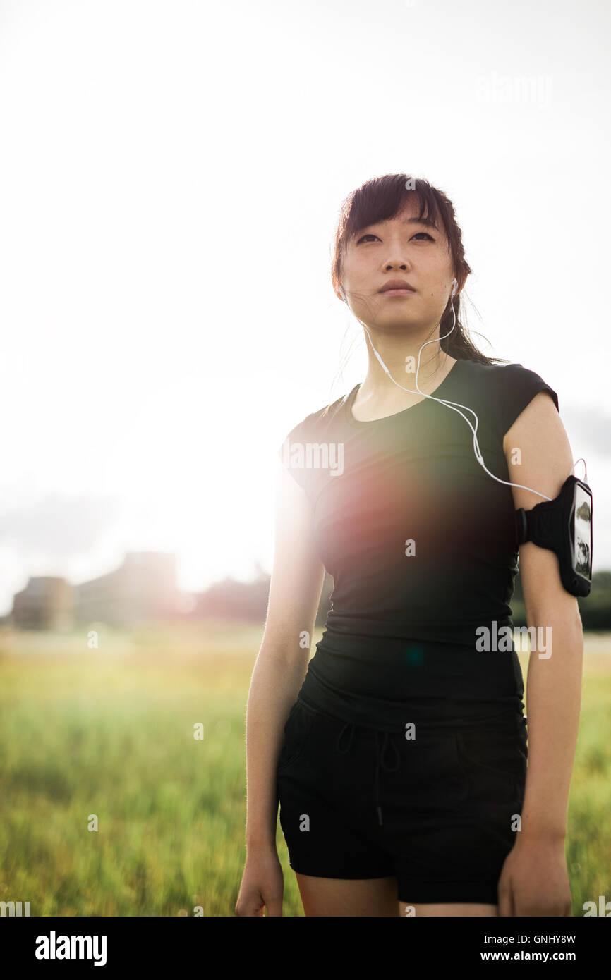 Vertikale Schuss von junge Chinesin in Sportbekleidung auf sonnigen Tag im Freien im Stadtpark stehen. Chinesische weibliche Läufer bereit für Stockfoto