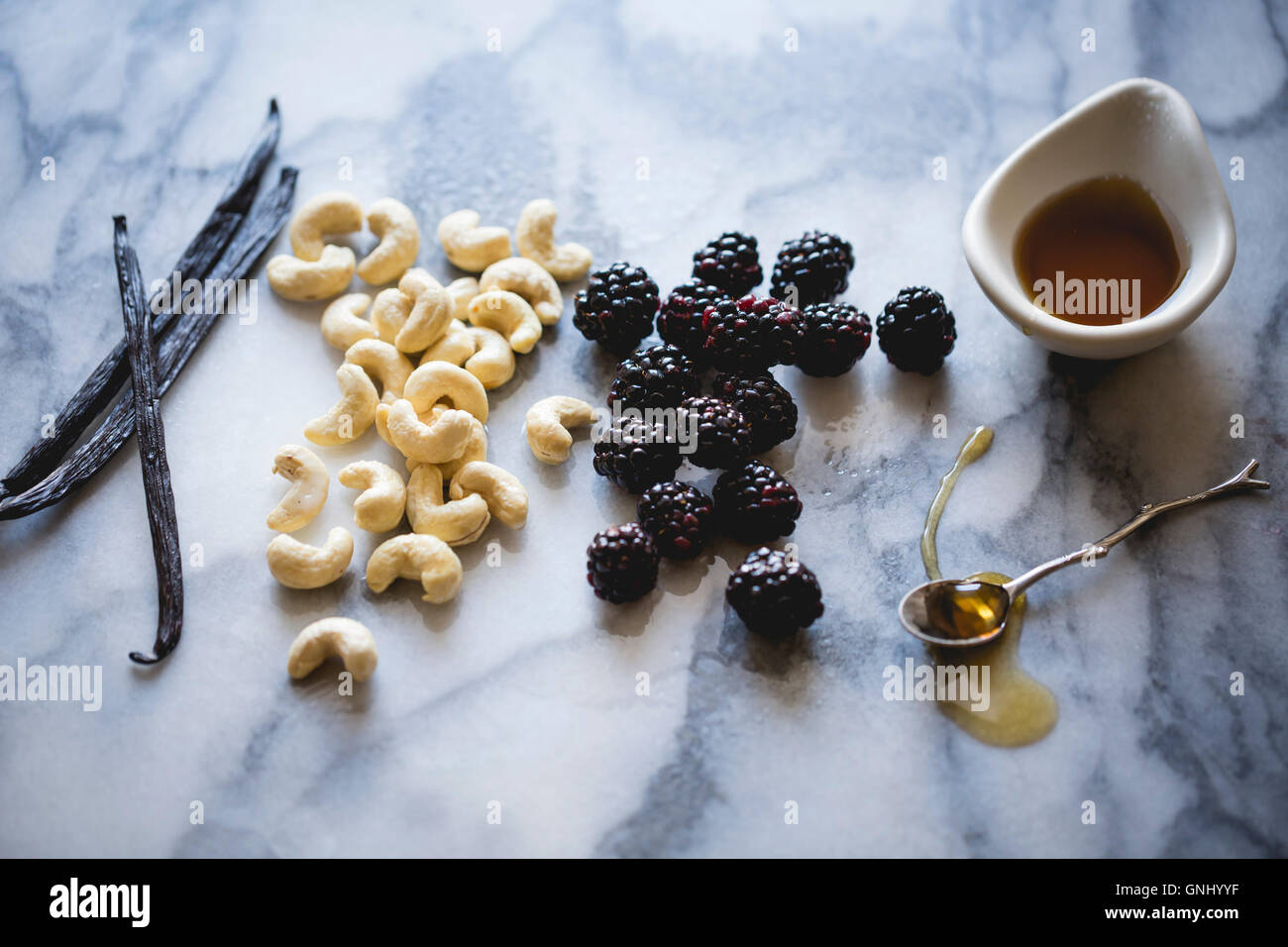 Zutaten auf eine Marmor-Arbeitsplatte. Brombeeren, Cashew-Nüssen, Honig, Vanille. Stockfoto