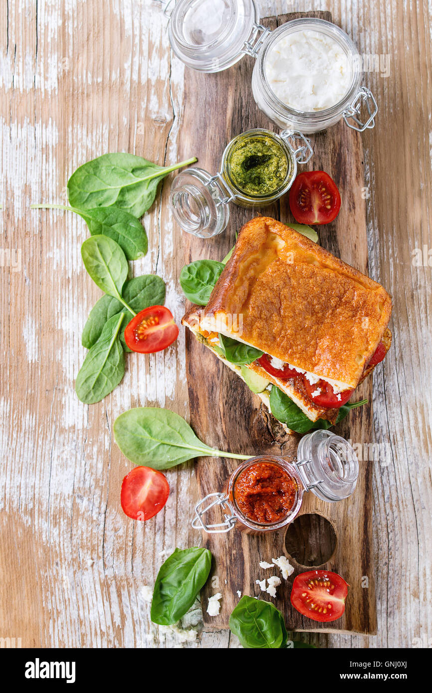 Low-Carb glutenfrei Cloud Brot vegetarischen Sandwich mit Spinat, Avocado, Feta Käse, Tomaten und Pesto-Sauce, serviert auf Messers Schneide Stockfoto