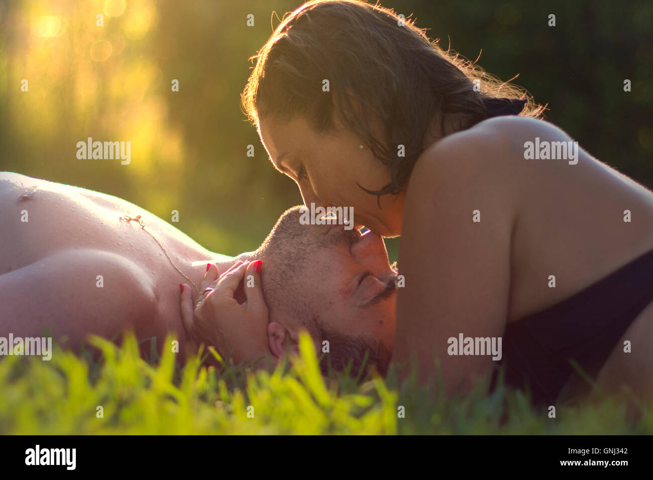 Frau und Mann liegen im Rasen zu küssen Stockfoto
