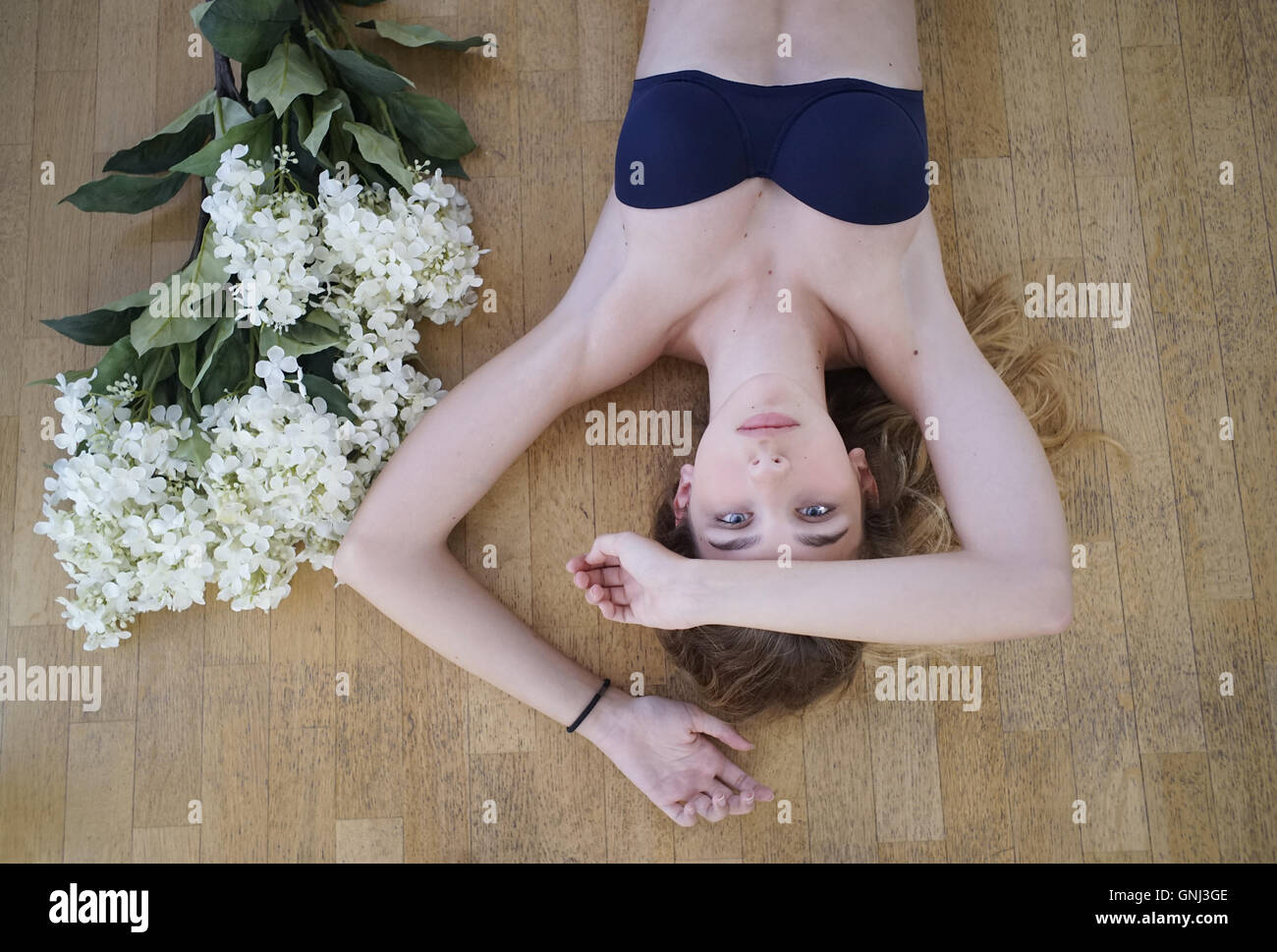 Blick von oben auf ein Mädchen, das auf dem Boden mit einem Blumenstrauß liegt Stockfoto