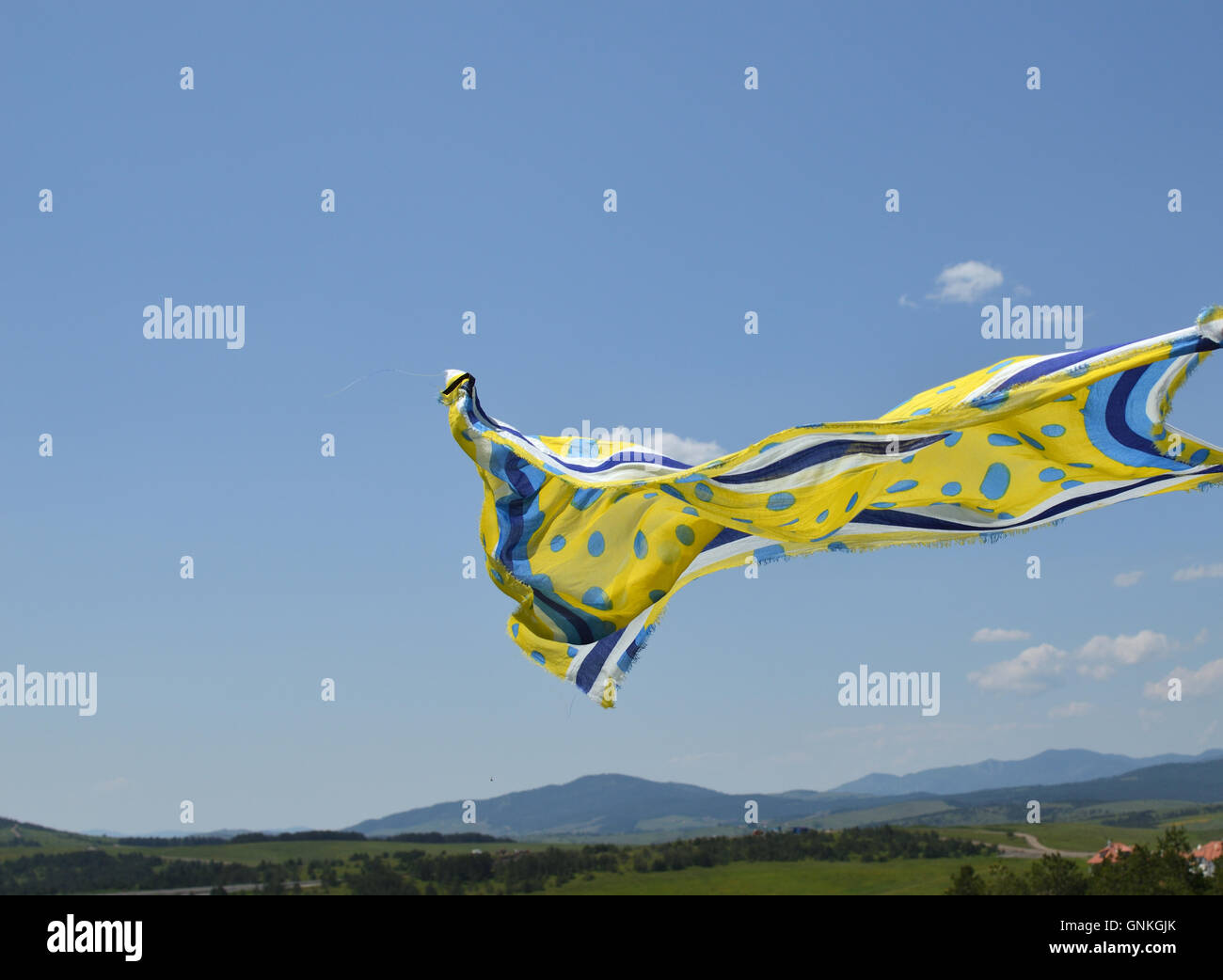 Gelbe und blaue Schal wehenden Wind mit blauen Himmel und Hügeln hinter Stockfoto