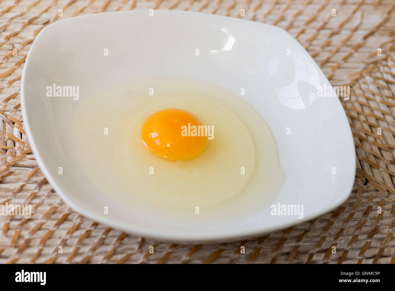 Rohes Ei auf einem weißen Teller bereit, mit einer Gabel vermischen Stockfoto