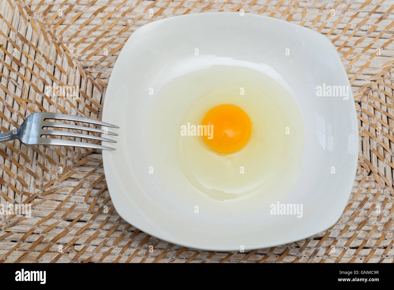 Rohes Ei auf einem weißen Teller bereit, mit einer Gabel vermischen Stockfoto