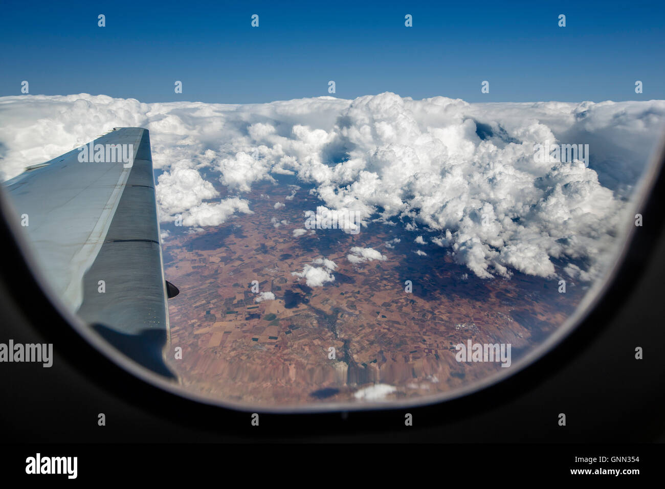 Flugzeugflügel während fliegen über den Wolken durch das Fenster gesehen Stockfoto