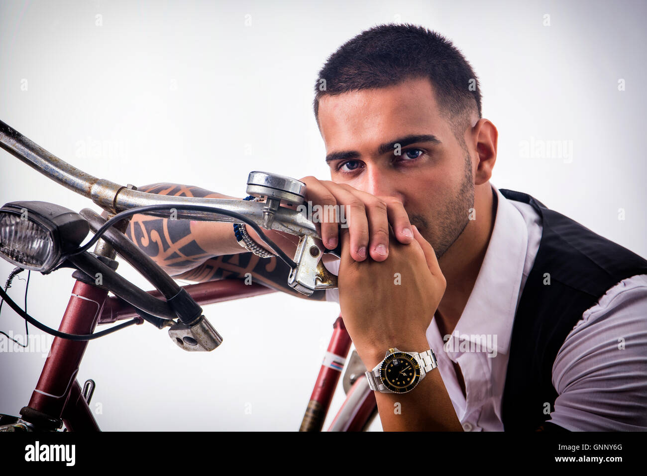 Porträt des jungen tätowierte Mann in eleganten Kleidern und Schuhen mit dem Fahrrad. Isolate.Studio erschossen. Stockfoto