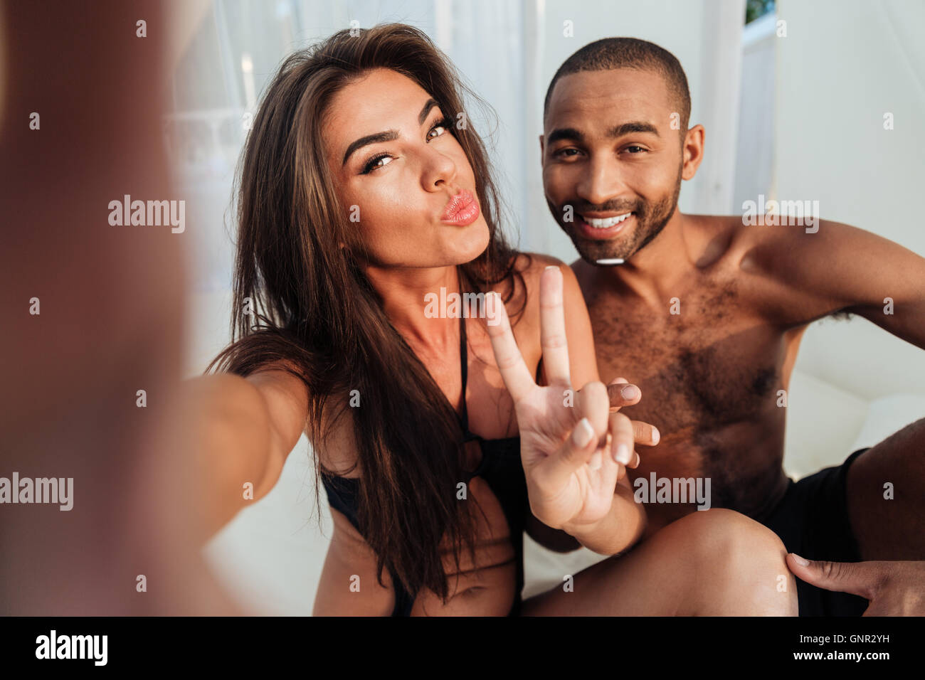 Junge Paar in Liebe machen Selfie beim Sitzen am Strand Bett und V Anzeichen lächelnd Stockfoto
