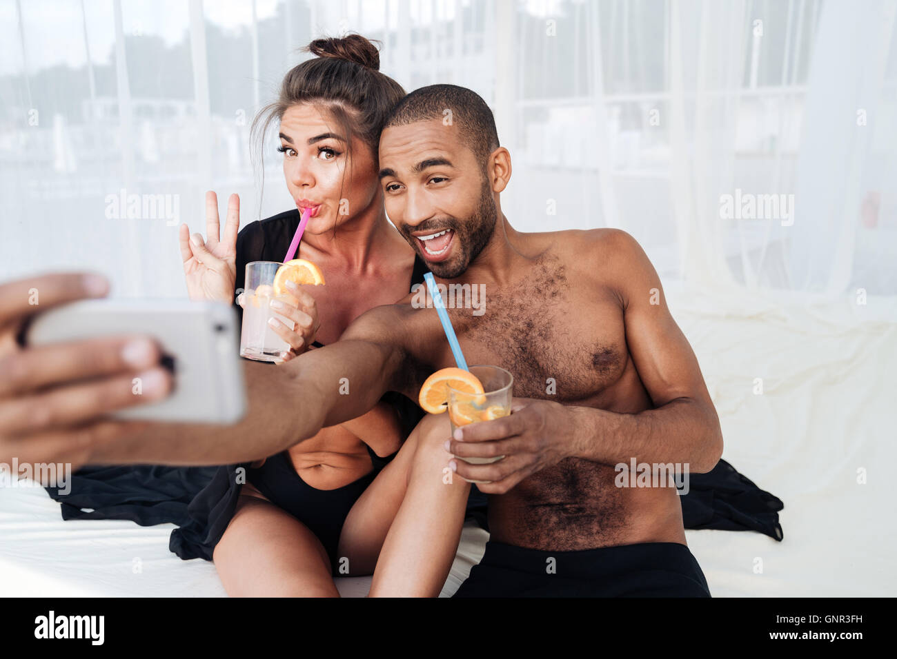 Glücklich lächelnd gemischtrassige paar Selfie machen und halten Cocktails am Strand Stockfoto