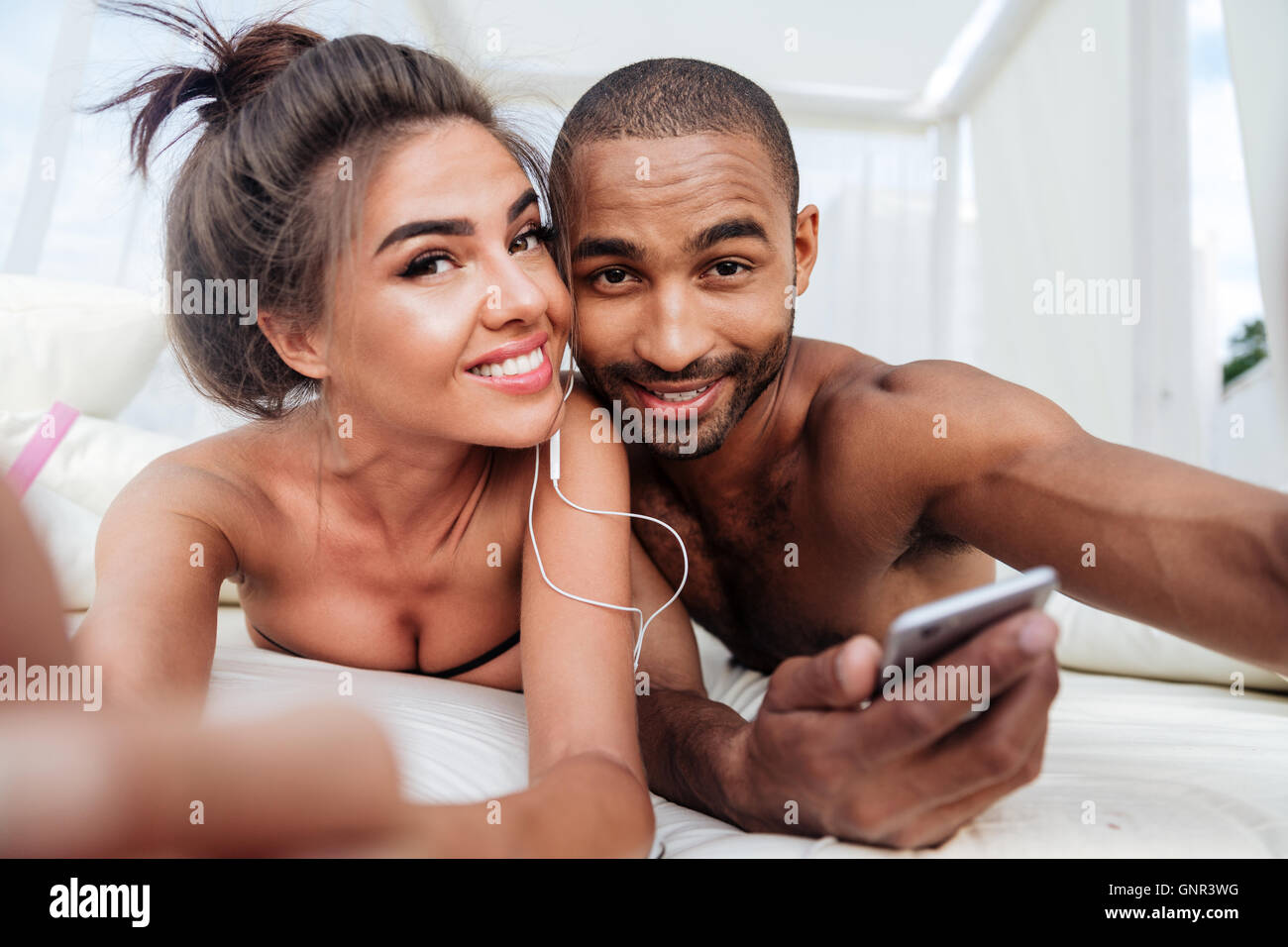 Junge schöne Brautpaar machen Selfie mit Smartphone und Verlegung auf der Strandliege Stockfoto