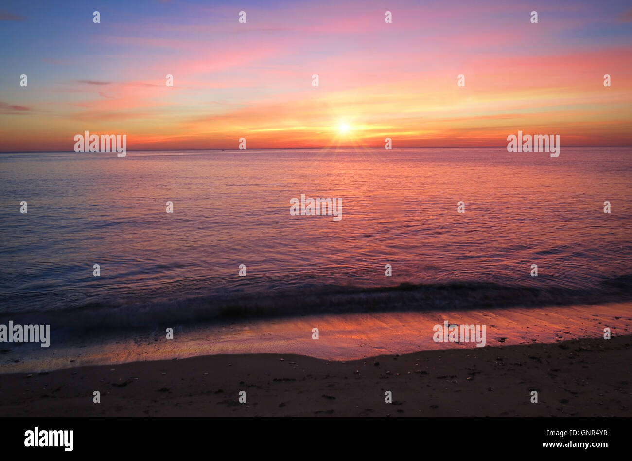 Bunter Himmel bei Sonnenuntergang am Nordstrand von Aberystwyth spiegelt sich in dem ruhigen Meer Stockfoto