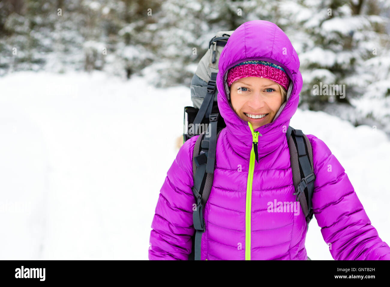Frau im weißen Wald Winterwald mit Rucksack wandern. Junge Mädchen gehen auf verschneiten Trail. Freizeit-Fitness und gesundes Leben Stockfoto