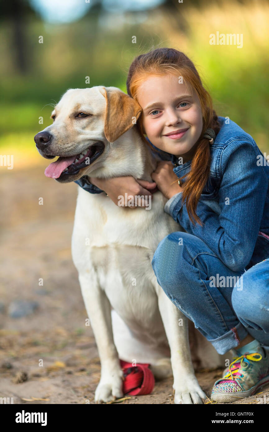 Kleine süße Mädchen umarmt Hund (Labrador) Stockfoto