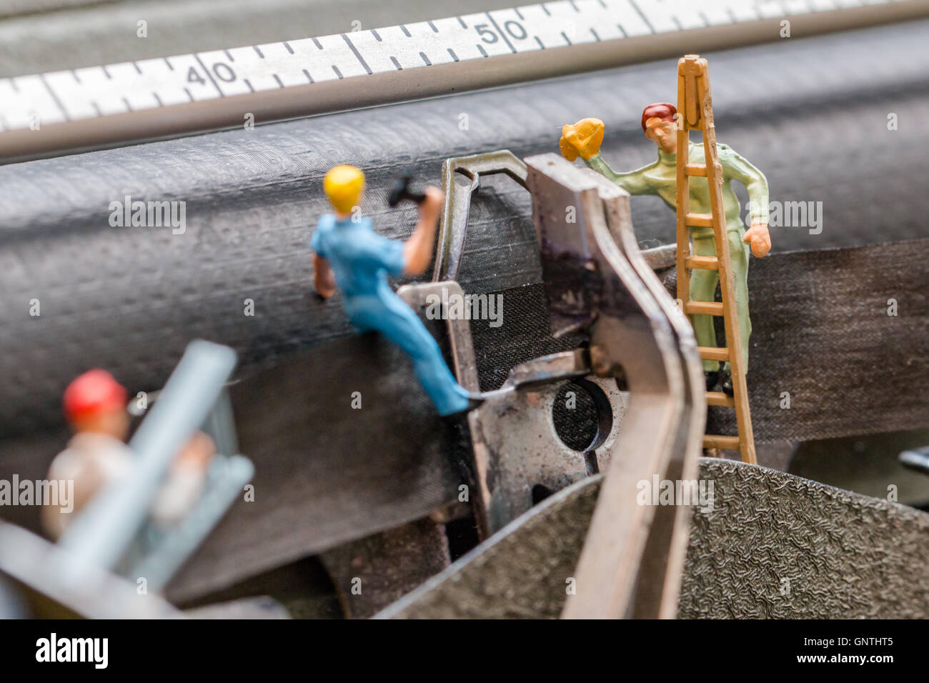 Miniatur-Menschen, die Arbeiten mit Leiter und Werkzeuge Stockfoto