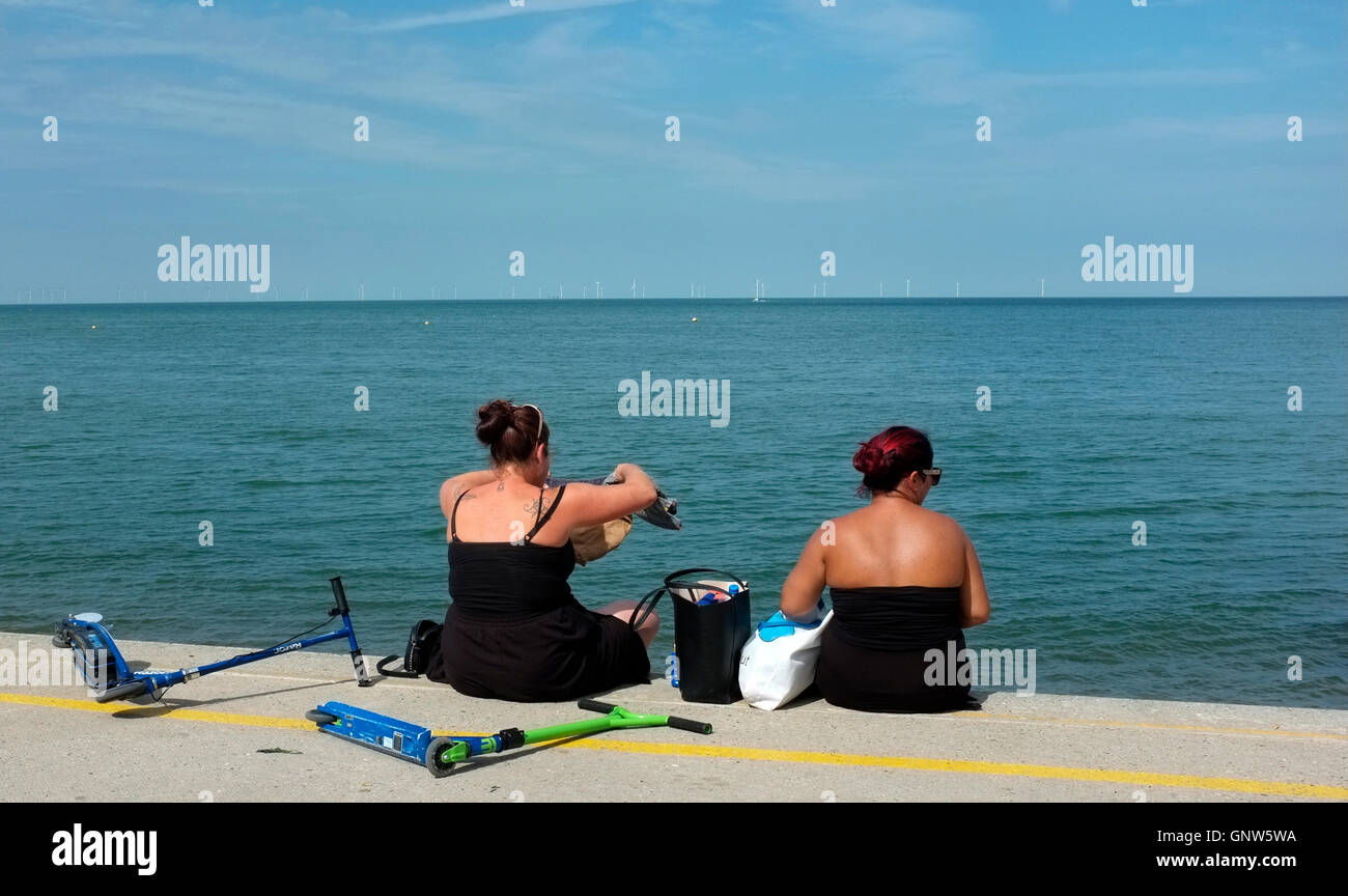 zwei Frauen sitzen auf Barriere Wand in Küsten Stadt Herne Bay im Osten Kent uk august 2016 Stockfoto