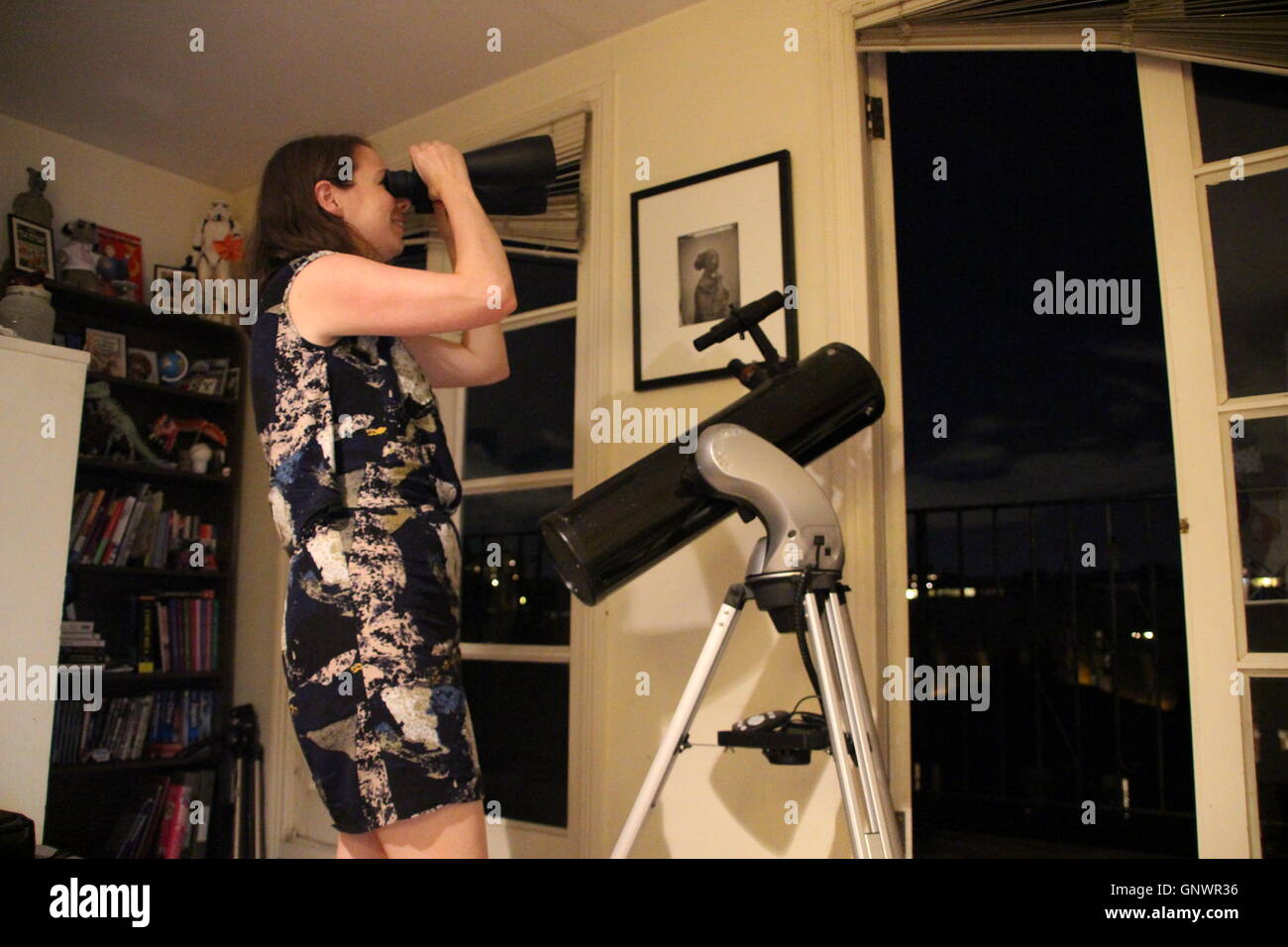 Frau auf der Suche in die Londoner Nacht Himmel stand neben Newtonschen Spiegelteleskop Celestron SkyMaster Fernglas Stockfoto