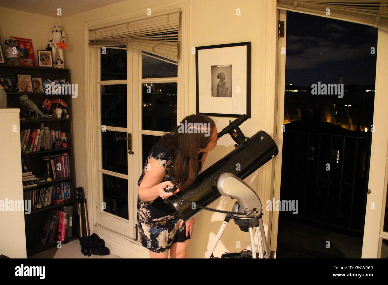 Frau auf der Suche durch Teleskop Skywatcher Explorer 130p aus Wohnung in London Stockfoto