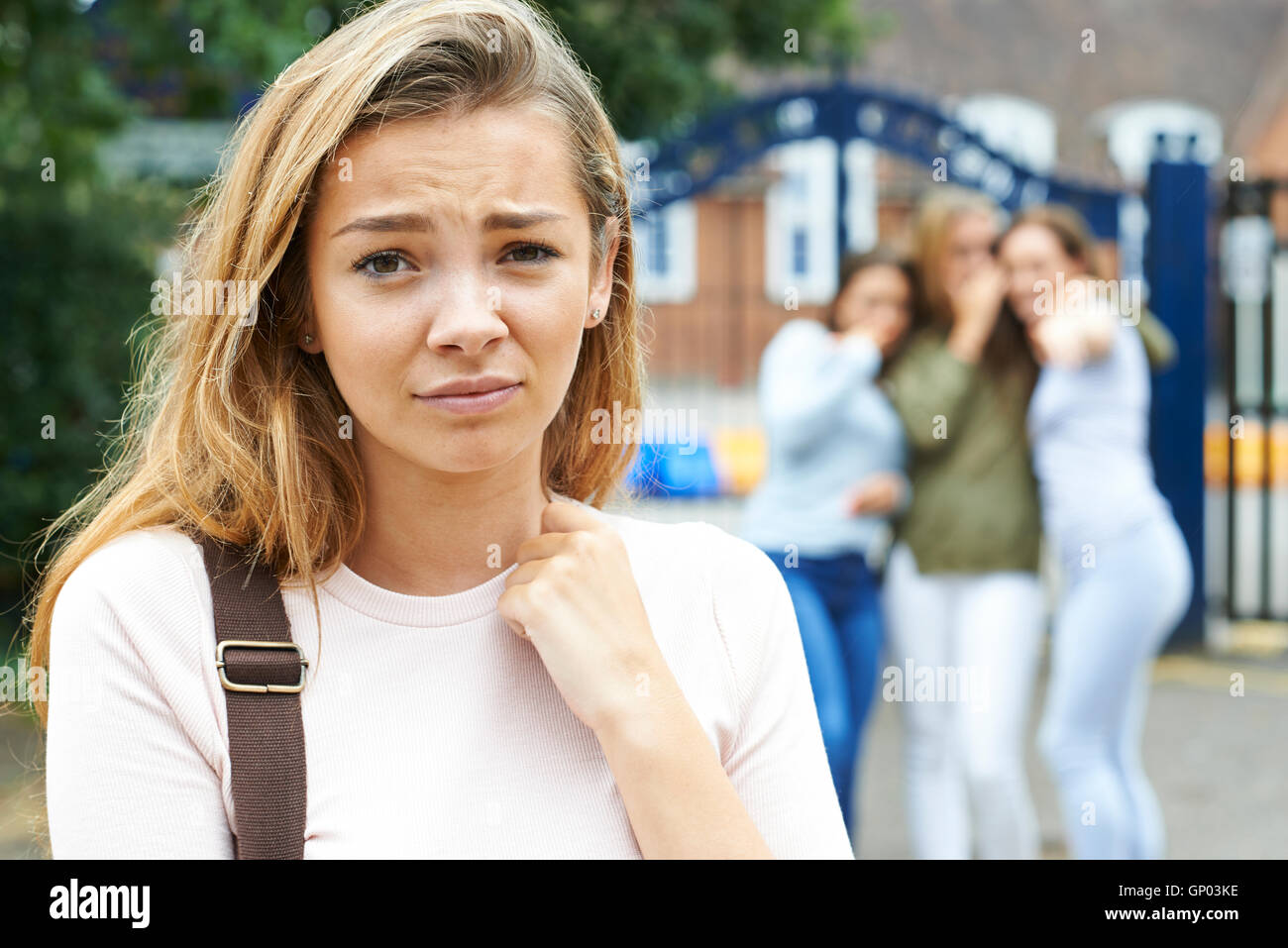 Unglückliche Mädchen wird durch Schulfreunde über geplaudert Stockfoto