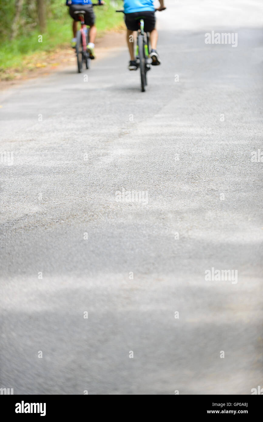 Rückansicht 2 verschwommen Bikers Radfahren auf dem Radweg in einem Park. Platz für Text. Geringe Schärfentiefe Stockfoto
