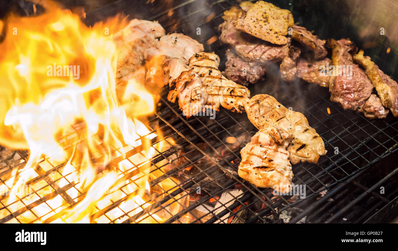 Verschiedene leckere Grillfleisch über der Flamme auf einem Grill Stockfoto