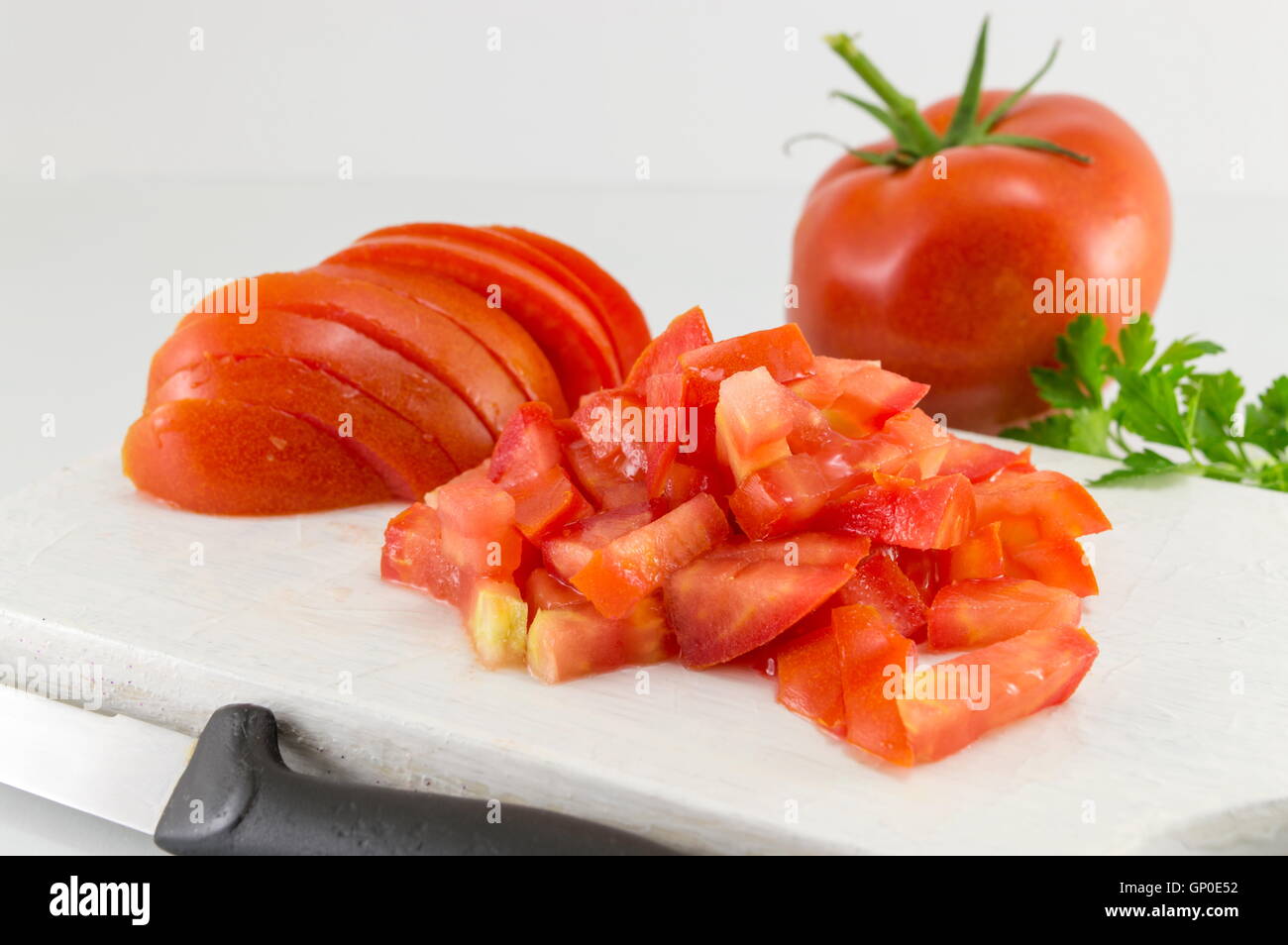 Frische Tomatenscheiben auf einem weißen Holzbrett Stockfoto