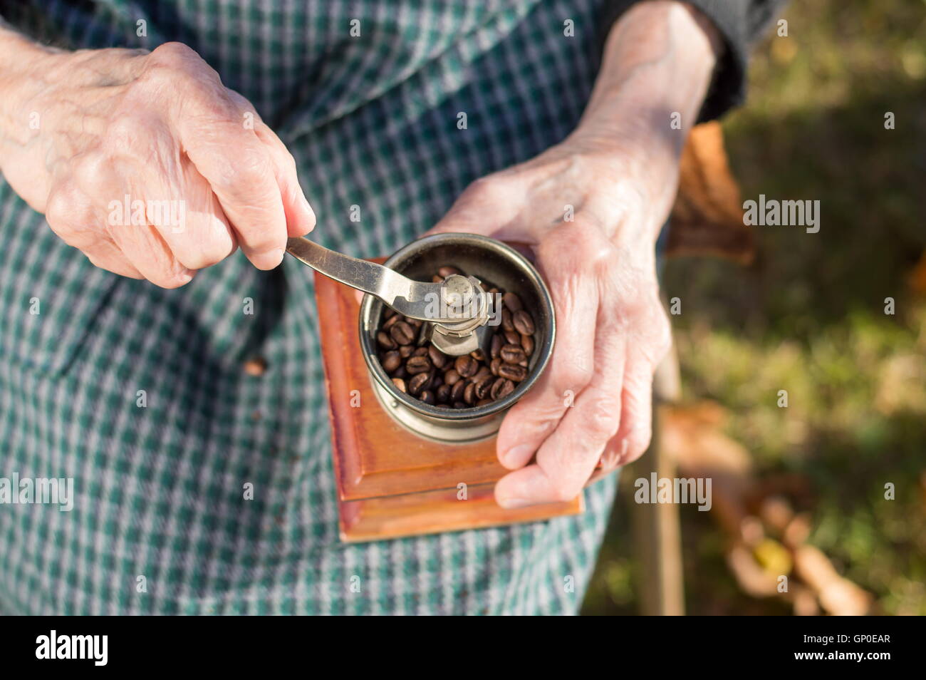 Ältere Frau Kaffee auf einem Vintage Kaffeemühle mahlen Stockfoto