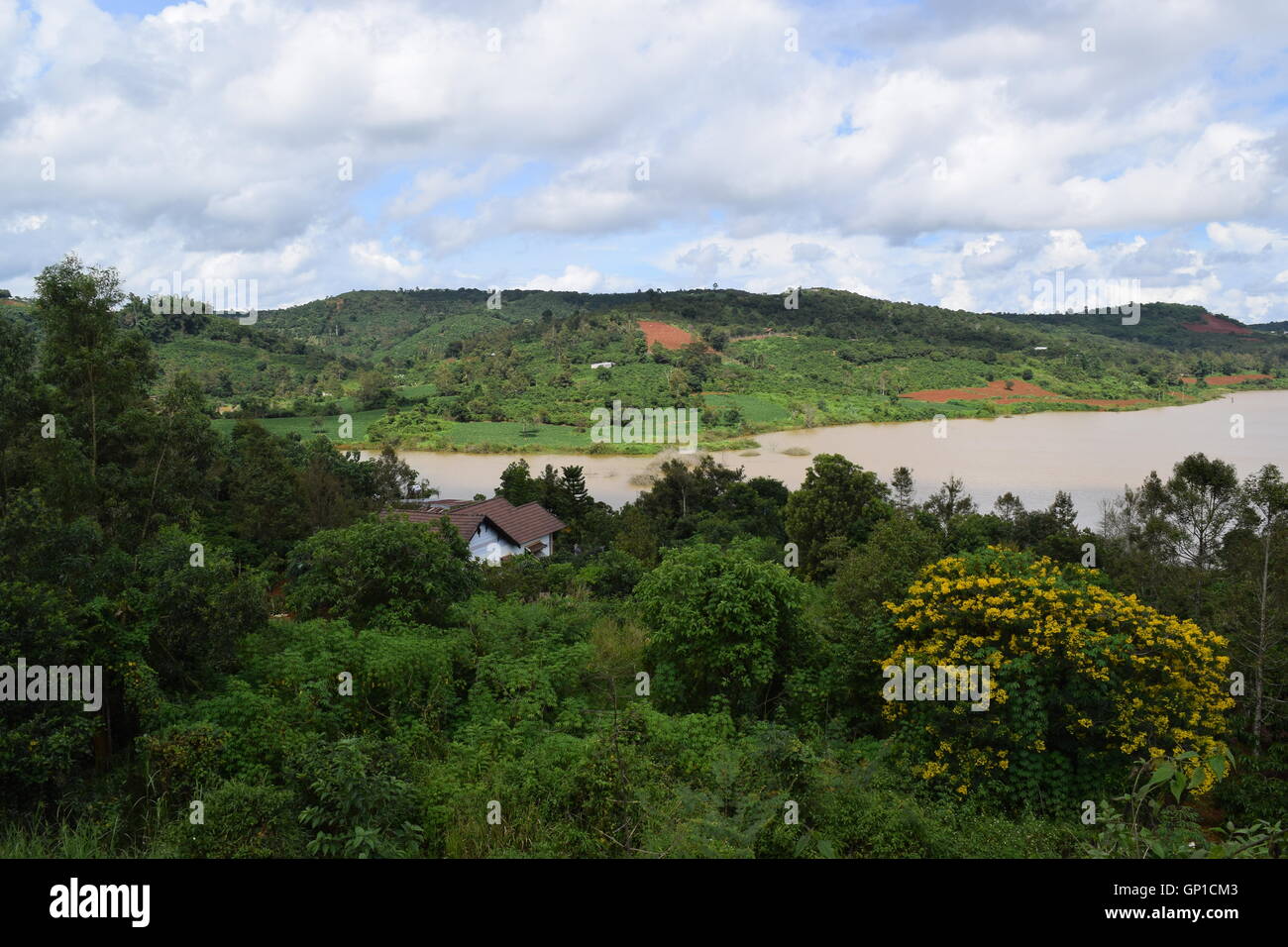 Hochland mit grünen Hügeln und einsamen Haus in der Nähe von River bank Dak R'Tih mit dramatischen Wolkenhimmel in Gia Nghia Stadt, Dak Nong, Filmkunst Stockfoto