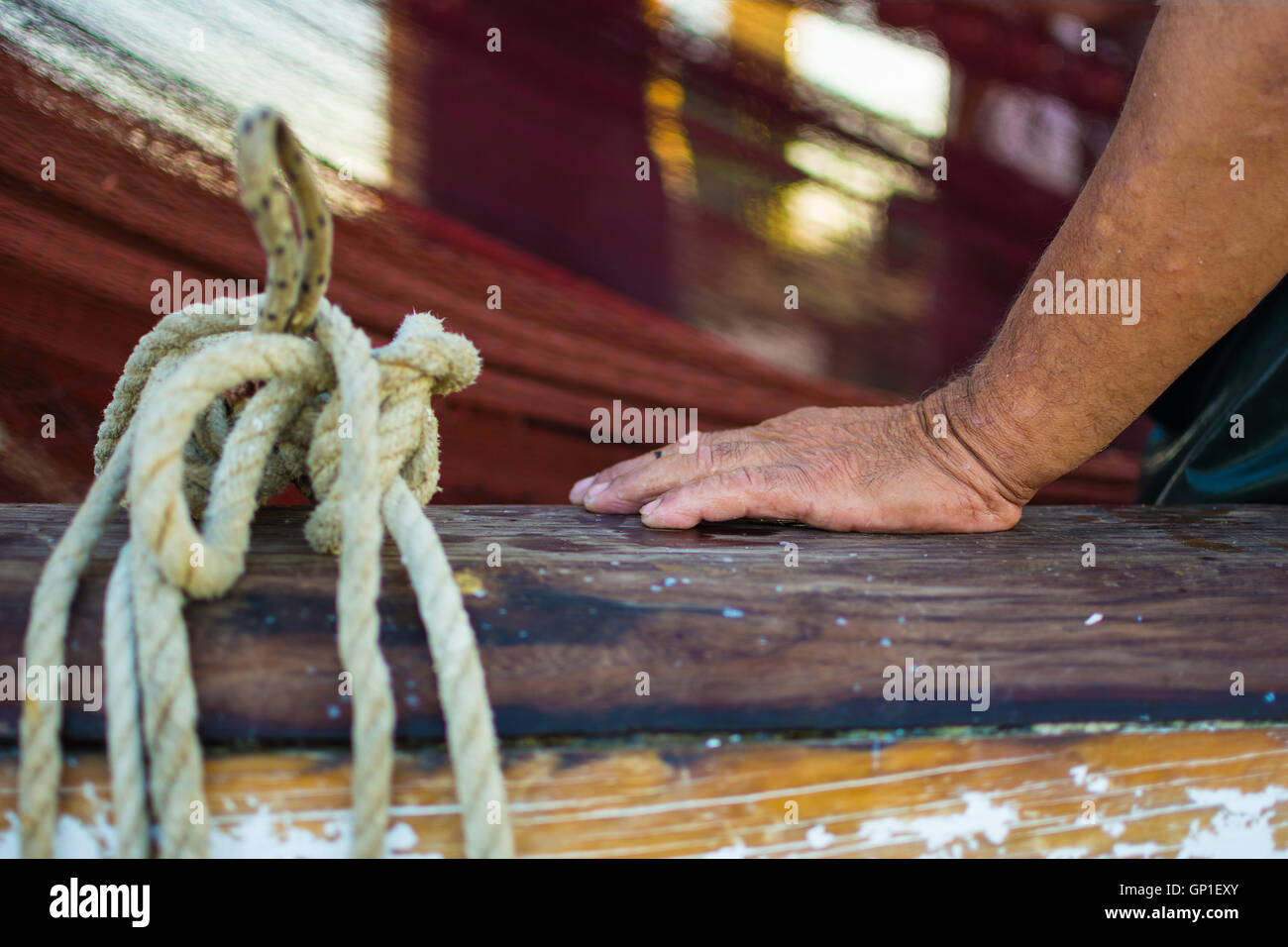 Fischers Hand mit Fischernetz im Hintergrund. Nass und faltige Hand auf einem Holzboot Zaun gelehnt. Stockfoto