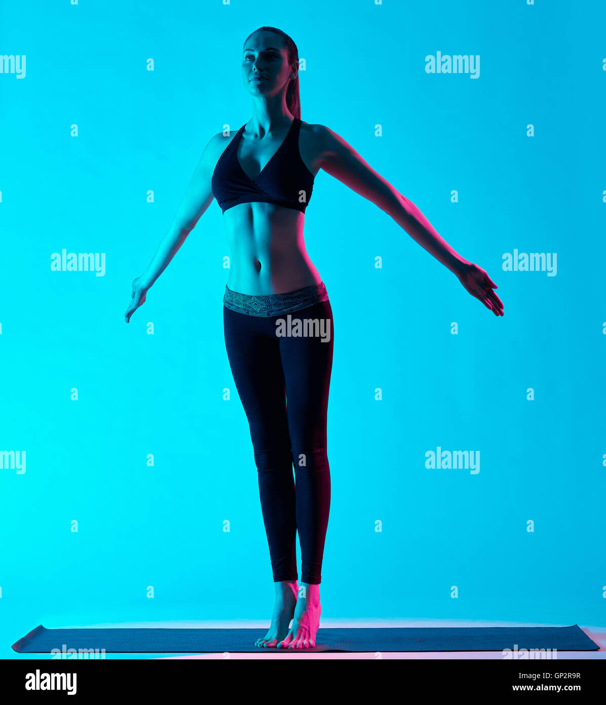 eine Kaukasische Frau Ausübung von Yoga-Übungen Tadasana Berg Pose im Silhouette Studio auf blauem Hintergrund isoliert Stockfoto