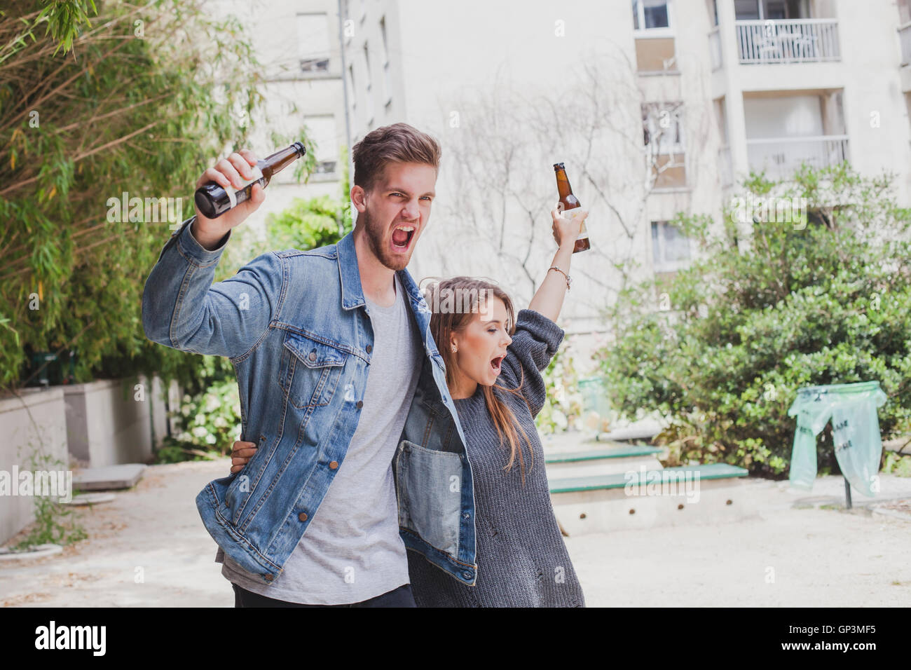 Betrunkene Leute singen auf der Straße, jungen Paar mit Bier Stockfoto