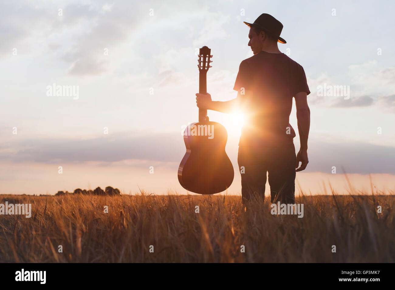 Silhouette der Musiker mit Gitarre bei Sonnenuntergang Feld Stockfoto