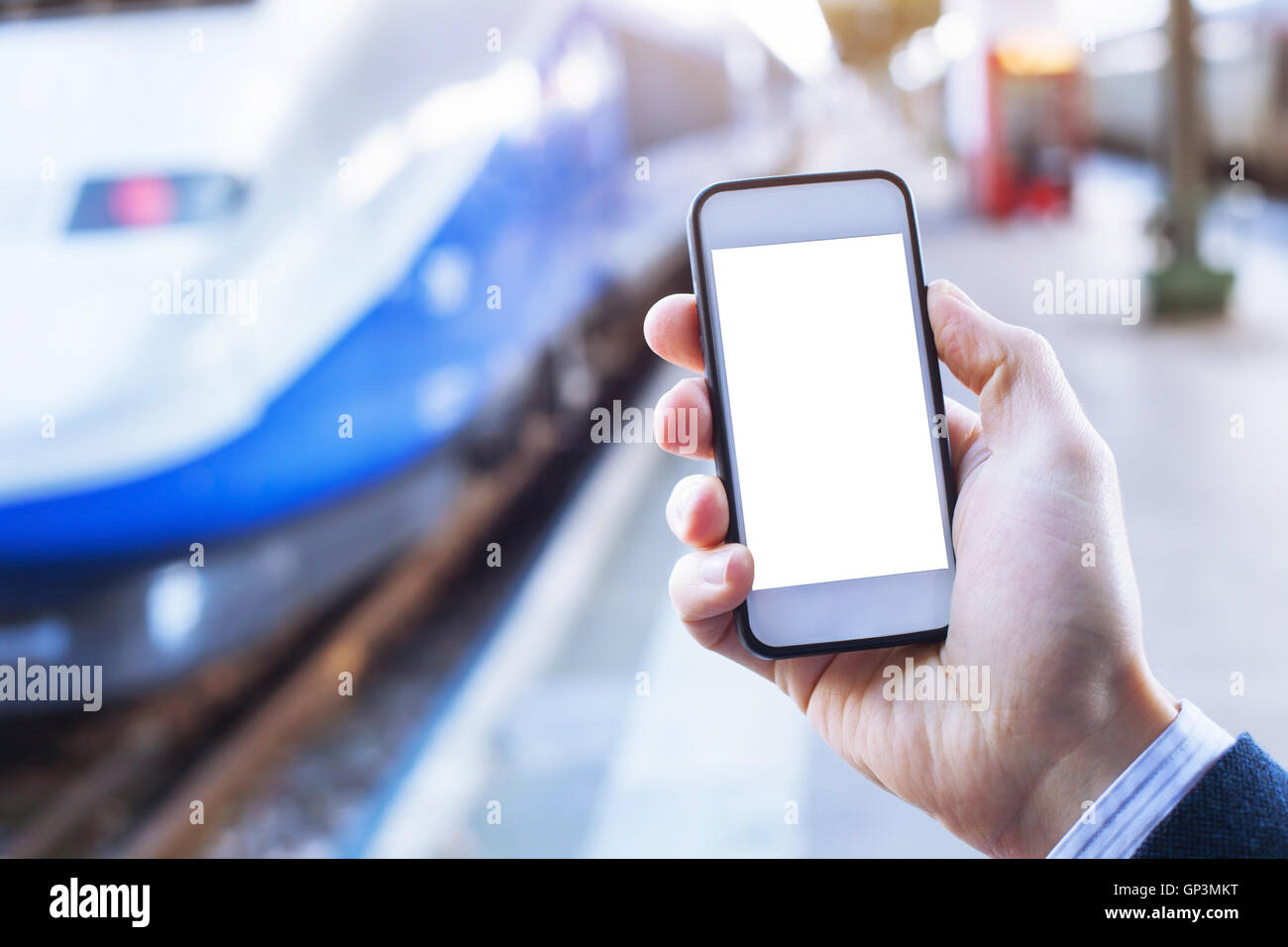 Hand mit Smartphone mit leeren Bildschirm im Bahnhof Stockfoto