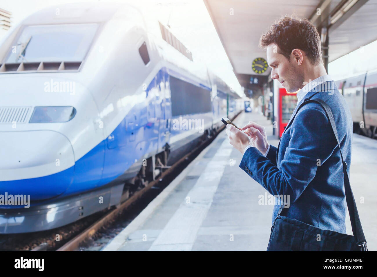 Mann mit mobilen Anwendung auf seinem Smartphone am Bahnhof, Geschäftsreisen Stockfoto