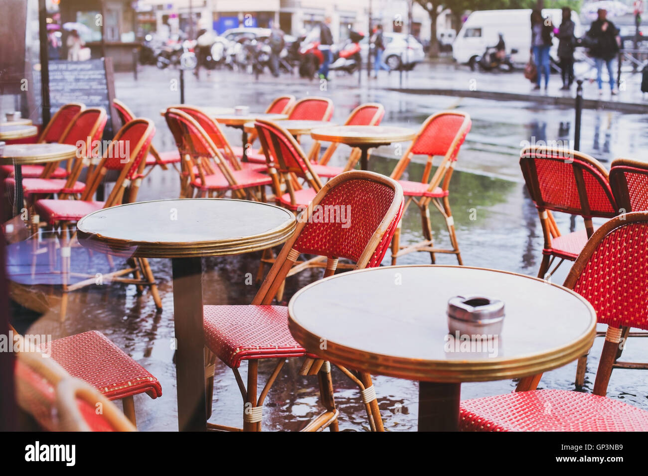Straßencafé in Paris in regnerischen Tag, rote Korbsessel und Tabellen Stockfoto